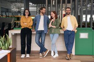 Team of young professionals is leaning on desk in modern open space office photo