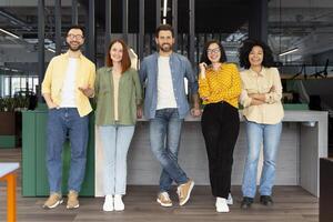 Diverse team of five creative people posing in modern office photo