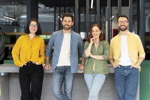 Startup team of four coworkers is leaning on desk in modern office photo