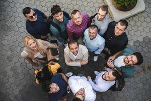 Top view photo of a group of business people and colleagues standing together holding hands, looking towards the camera, symbolizing unity and teamwork.