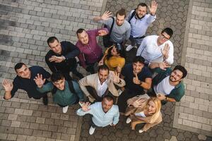 Top view photo of a group of business people and colleagues standing together holding hands, looking towards the camera, symbolizing unity and teamwork.