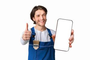 Painting Works. Young Handyman With Paintbrush In Pocket Showing Thumb Up Gesture, Posing Over Light Background With Copy Space photo