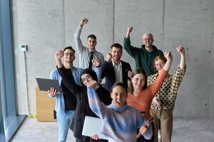 A diverse team of business professionals ecstatically celebrating their success in a modern office, expressing triumph and unity after achieving their goals photo