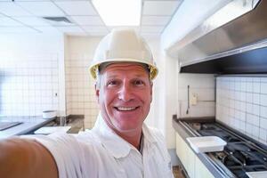 A man in a white hard hat taking a selfie photo