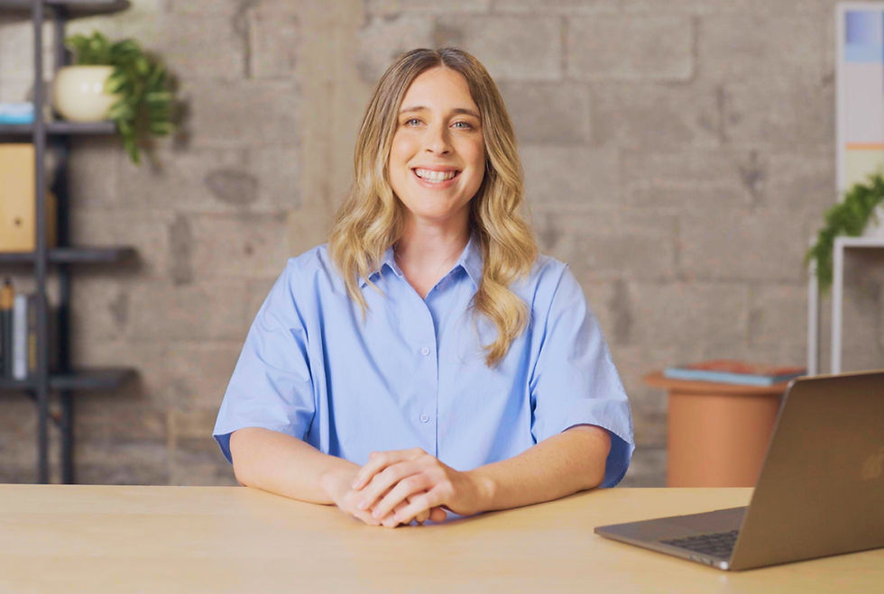 A apresentadora do curso Wix Studio Essentials sentada de frente para a câmera em uma mesa com um MacBook.