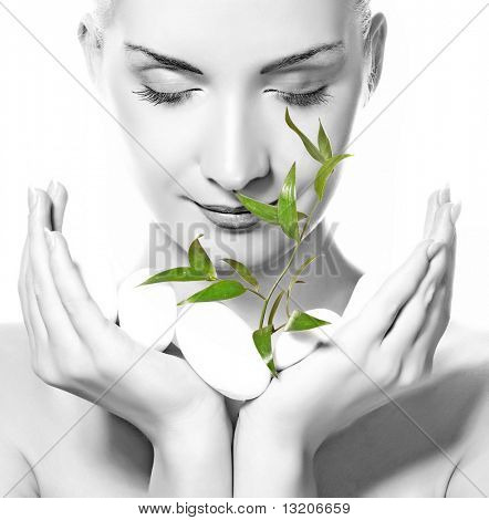 Beautiful young woman holding plant growing up through stones