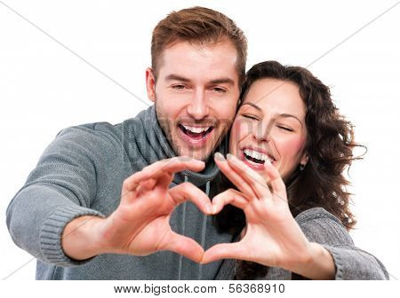 Valentine Couple. Portrait of Smiling Beauty Girl and her Handsome Boyfriend making shape of Heart by their Hands. Happy Joyful Family. Love Concept. Heart Sign. Laughing Happy Lovers. Valentines Day