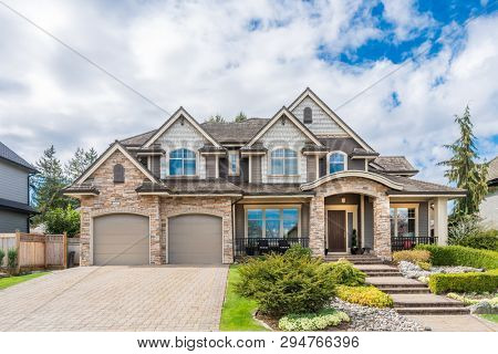 Beautiful exterior of newly built luxury home. Yard with green grass and walkway lead to front entrance.