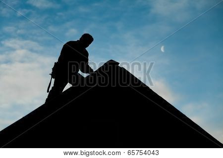 Contractor In Silhouette Working On A Roof Top