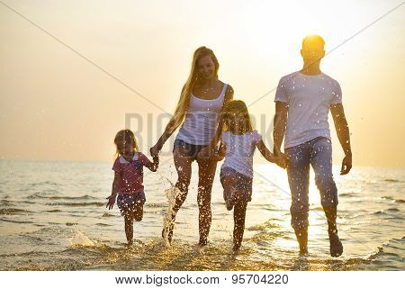 Happy Young Family Having Fun Running On Beach At Sunset. Family Traveling Concept