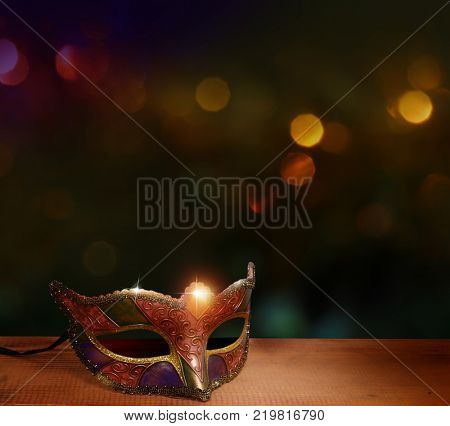 Traditional female carnival venetian mask; on table .Masquerade; mask on; glitter background.Mardi Gras.