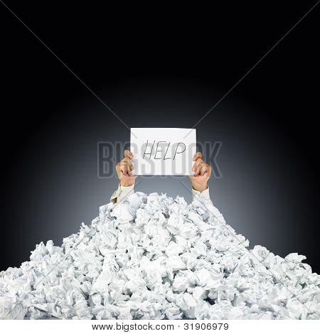 Person under crumpled pile of papers with hand holding a help sign