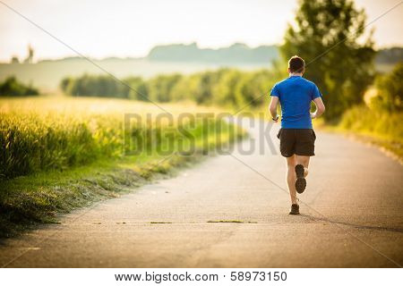 Male athlete/runner running on road - jog workout well-being concept