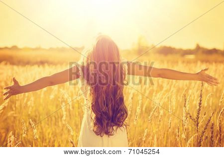 Autumn Girl enjoying nature on the field. Beauty Girl Outdoors raising hands in sunlight rays. Beautiful Teenage Model girl in white dress running on the Field, Sun Light. Glow Sun. Free Happy Woman