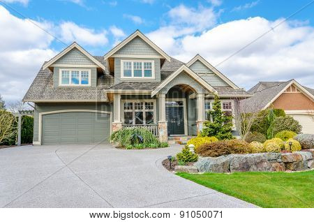 Luxury house with a two-car garage and beautiful landscaping on a sunny day. Home exterior.