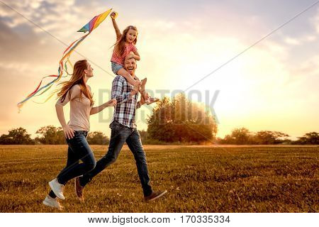 family running through field letting kite fly