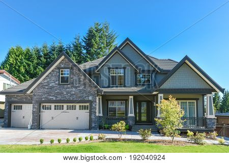 Brand new luxury residential house with big garage for three cars. Family house with concrete driveway and green lawn in front