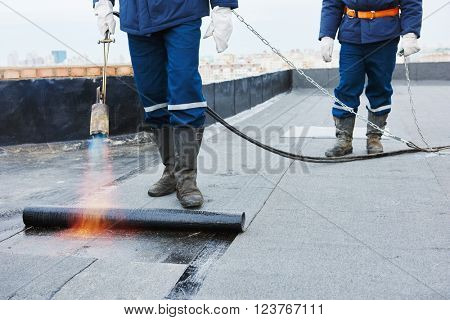 Flat roof installation. Heating and melting bitumen roofing felt 