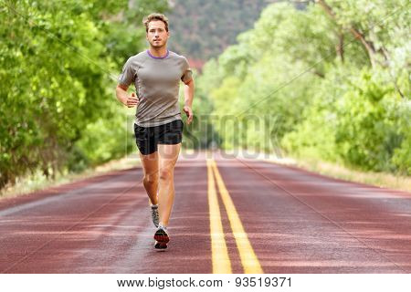 Sport and fitness runner man running on road training for marathon run doing high intensity interval training sprint workout outdoors in summer. Male athlete sports model fit and healthy aspirations.