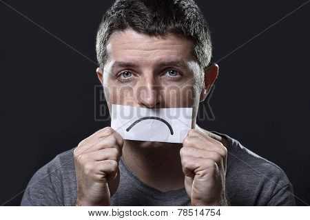 Young Depressed Man Lost In Sadness And Sorrow Holding Paper With Sad Mouth In Depression Concept