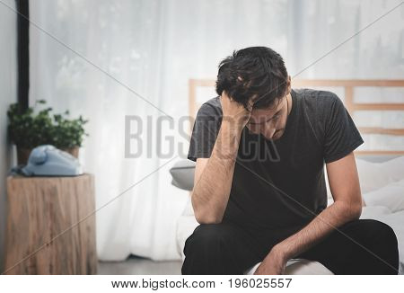 Stressed and Sad Handsome man sitting on the bed. Disappointment Depression Anxiety and disorder concept with copy space.