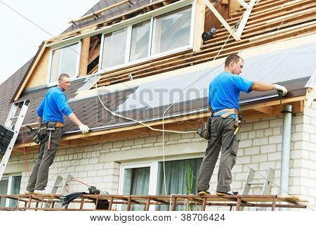 two workers on roof at works with flex tile material measuring roofing drain distance