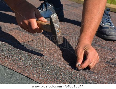 Roofing Contractor Laying Asphalt Shingles. House Roofing Construction With Roofing Shingles. Roofer