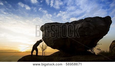 Man pushing a boulder on a mountain