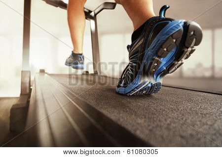 Man running in a gym on a treadmill concept for exercising, fitness and healthy lifestyle