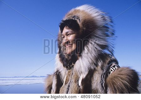 Smiling Eskimo woman wearing traditional clothing in wind against clear blue sky