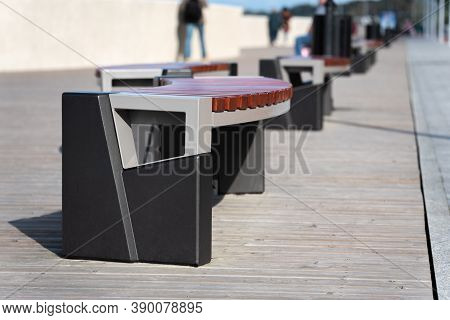 Modern Curved Benches Line The Sidewalk. The Boardwalk Is Located On The Sea Coast. A Place To Sit A