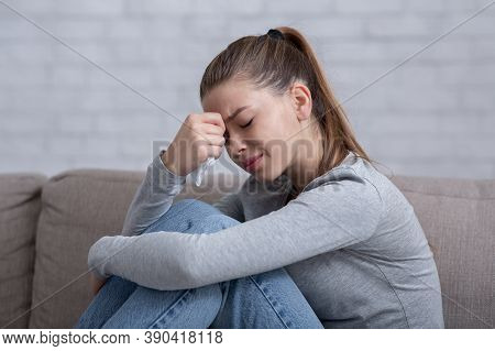 Lonely Millennial Woman Feeling Hopeless Or Desperate, Crying On Sofa At Home. Sad Young Lady Suffer