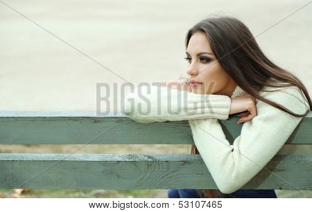 Young lonely woman on bench in park