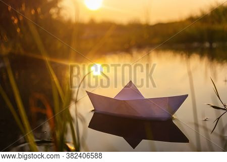 A Paper Boat Floats On The Water At Dawn. Creative Concept Of Outdoor Recreation, River, Travel. Coz