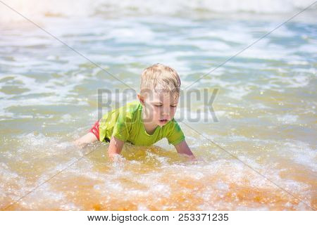 Little Boy Swimming In The Sea, Running And Splashing In The Waves Of Pure, Happy Baby