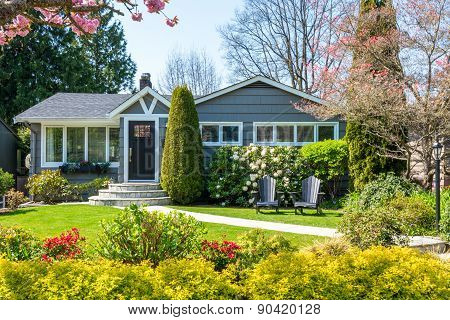 Cozy house with beautiful landscaping on a sunny day. Home exterior.