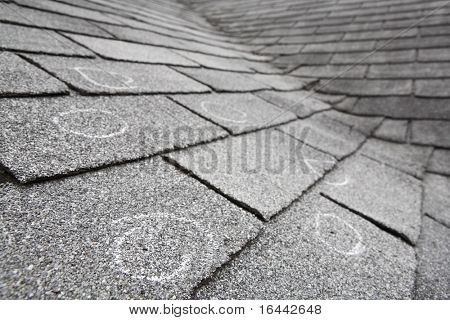 Old roof with hail damage, chalk circles mark the damage. Shallow depth of field