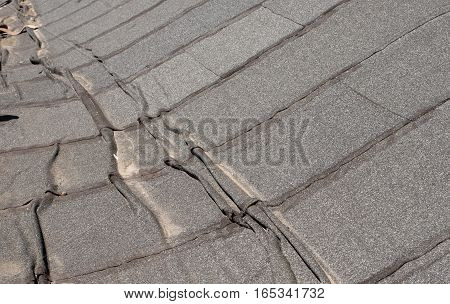 Damaged insulation layer of the roof. Destruction flat roof due to temperature changes. Damaged waterproofing flat roof. Crack roofing felt. Damaged roofing felt. Old roofing felt