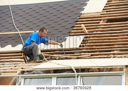 worker on roof at works with flex tile material demounting roofing