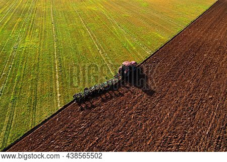 Tractor With Plough On Plowed. Ploughing And Soil Tillage. Agricultural Tractor On Cultivation Field