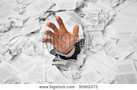 Hand reaches out from big heap of crumpled papers