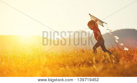 happy child girl with a kite running on meadow in summer in nature