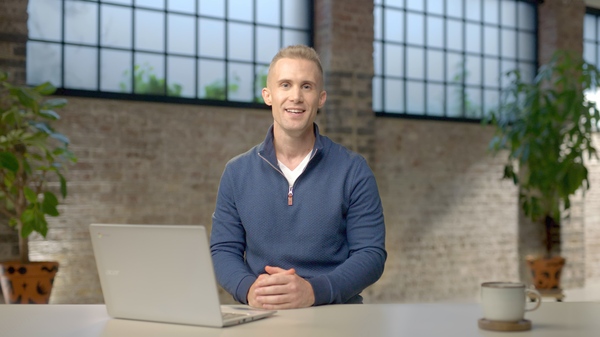 Image of a person sitting on a desk with a laptop and delivering a training session on Artificial Intelligence