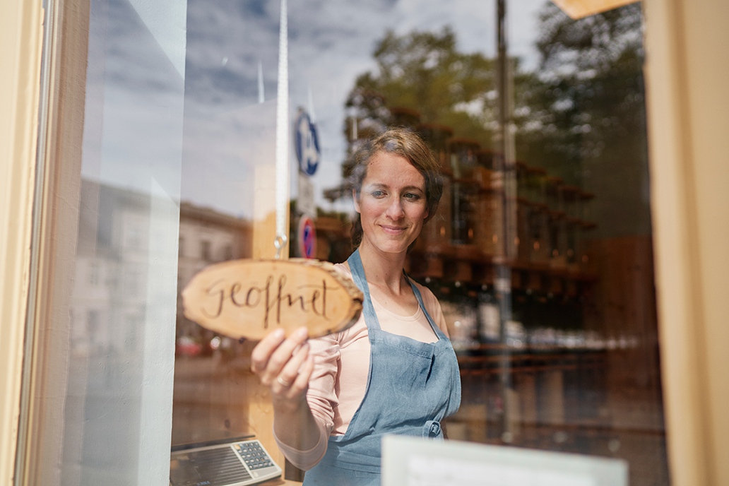 Mitarbeiterin eines Einzelhandelsgeschäfts hinter dem Schaufenster ihres Ladens