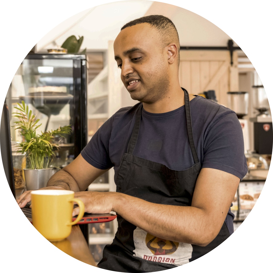 Dawit Abraham of Passion Ethiopian Coffee perches at a breakfast bar in his bright, airy cafe, as he works at a laptop.