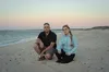 A man and a women crouched down on a beach