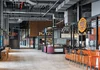 A large industrial space with new food kiosks in bright colors with stools to sit and enjoy meals.