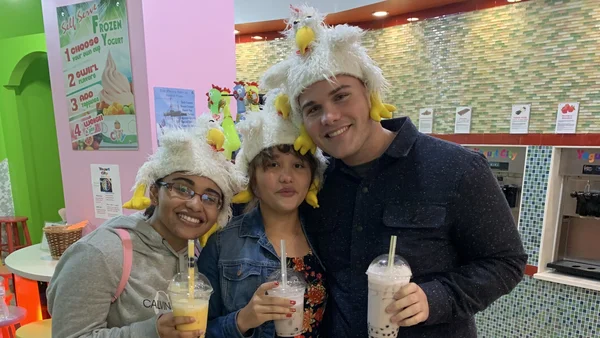 Photo of Deyrel Diaz with his two younger sisters. All are holding boba drinks, looking at the camera, smiling.