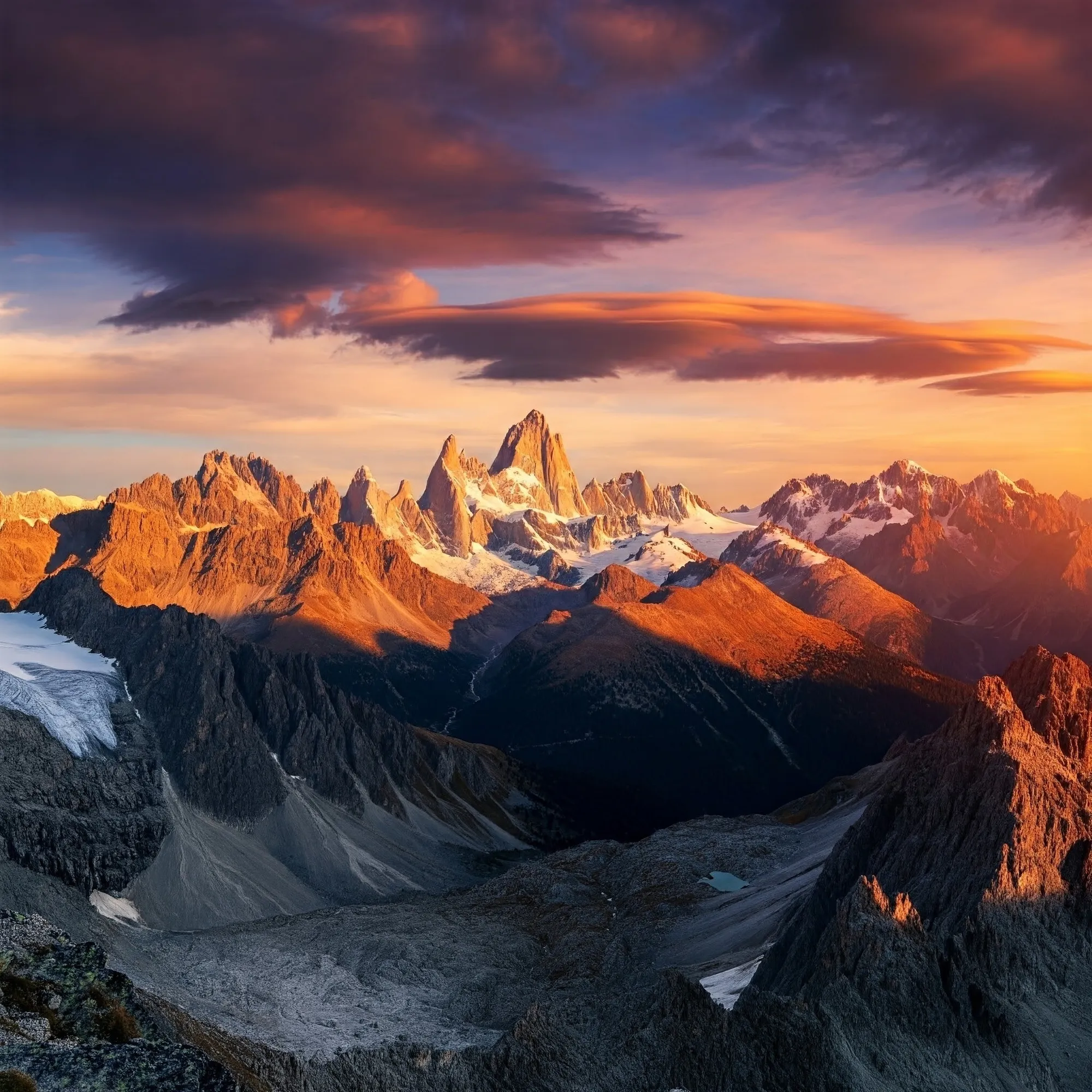 A photorealistic image of a breathtaking mountain vista with jagged peaks and snow-capped summits, bathed in the warm glow of a setting sun. Dramatic clouds, painted in vibrant hues of orange, pink, and purple, streak across the sky, casting long shadows across the rugged landscape.