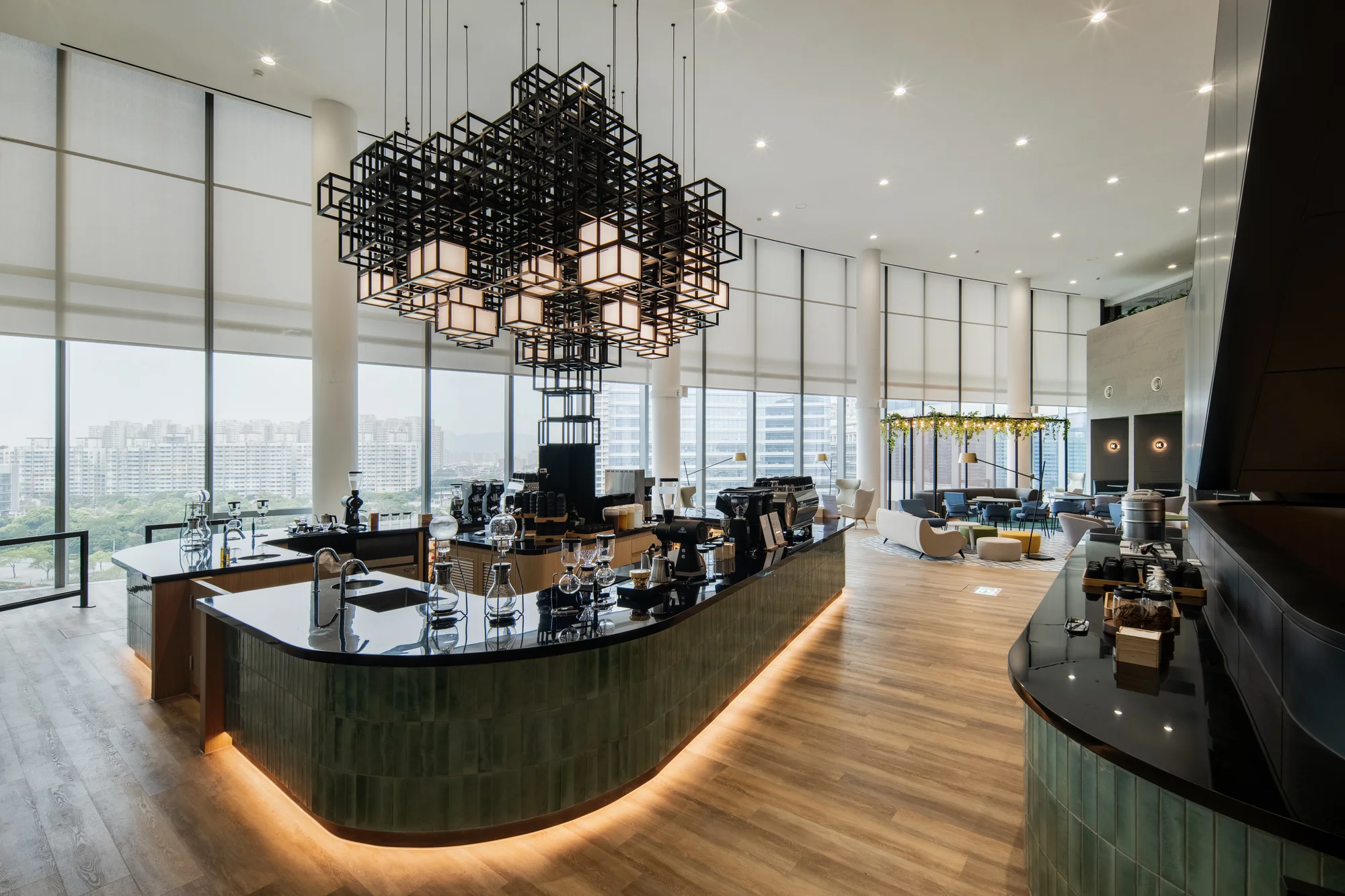 A cafe room with a black geometric ceiling lamp, black marble counterspace and glass coffee beakers.